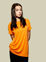 A woman in an orange shirt poses for the camera. The image has a bright and cheerful mood, as the woman's outfit and the color of the shirt create a sense of warmth and happiness