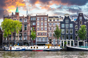 Obraz premium The unique architecture of Amsterdam at twilight, showing the old city merchant buildings and boats along the canal.