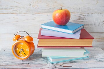 Alarm clock and stack of books on wooden background. Back to school concept.
