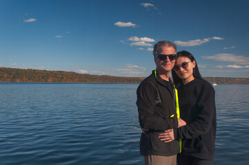 a happy couple in front of Cayuga lake new york in autumn