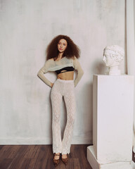 Portraits of an attractive girl with curly hair and a slim figure in the studio