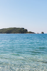 Island in blue sea with clear water. Summer seascape, natural tranquility, and peaceful horizon in Mediterranean environment.