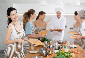Young lady who attends group class of culinary school cuts up chicken and prepares low-calorie diet lunch
