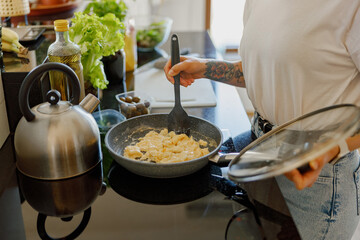 A skilled chef prepares delicious pasta in a stylish, modern kitchen brimming with fresh, vibrant...