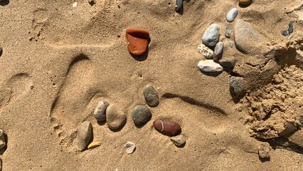 Beach pebbles form abstract sandy alphabet, invoking summer solstice celebrations and eccentric coastal stone poetry gatherings