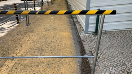 Yellow-black striped barrier on dusty walkway, urban aesthetics meet minimalist caution,...