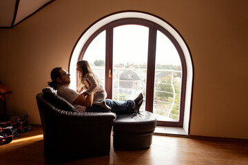 Father and daughter enjoy a peaceful moment in a cozy room with an arched window. Sunlight streams in, casting a warm glow as they share quality time together, fostering a strong family bond
