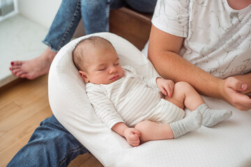 Newborn baby sleeping peacefully on father's lap, enjoying the warmth and comfort of his presence, creating a heartwarming scene of family bonding and paternal love