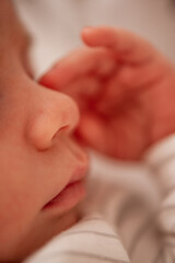 Close-up of a newborn baby sleeping peacefully, with their small hand gently resting near their face, conveying a sense of tranquility and innocence