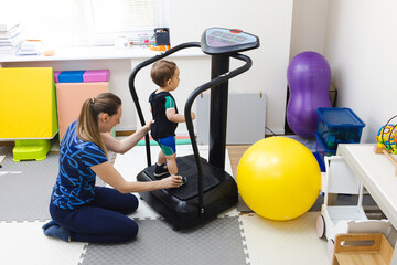 Physiotherapist during vibration therapy for boy patient using vibration platform for balance and coordination in rehabilitation clinic