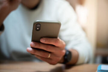A close-up shot of male hands holding and interacting with a smartphone. The scene focuses on everyday tech usage, communication, and connectivity in daily life.
