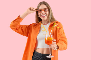 Young woman in sunglasses with aperol spritz cocktail on pink background
