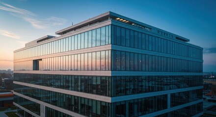Obraz premium Modern glass building reflects the sunset