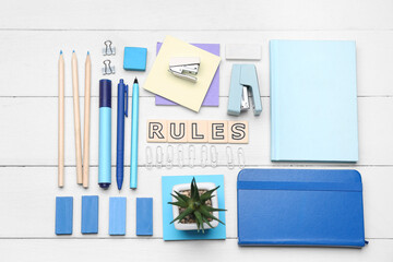 Word RULES with stationery supplies on white wooden background