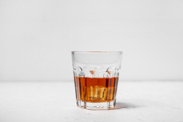 Glass of rum with ice cubes on white background