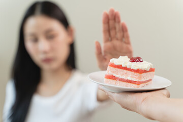Dieting young asian woman or girl use hand push out, dent sweet cake and control temptation for...