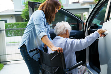 Caregiver help Asian elderly woman disability patient use wheelchair to get in car.