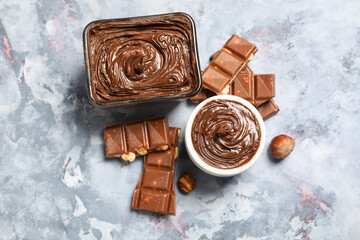 Bowls of tasty chocolate spread with hazelnuts on blue grunge background