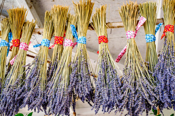 Bunches of dried lavender hang from a display at a local market, showcasing vibrant colors and...