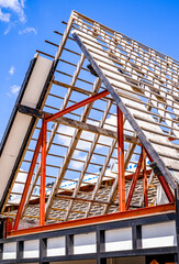 Construction progress of a building with exposed roof structure showcasing modern architectural design under clear blue sky