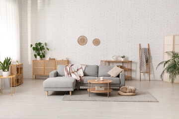 Interior of living room with comfortable grey sofa, poufs and table