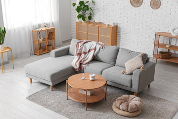 Interior of living room with comfortable grey sofa, poufs and table, closeup