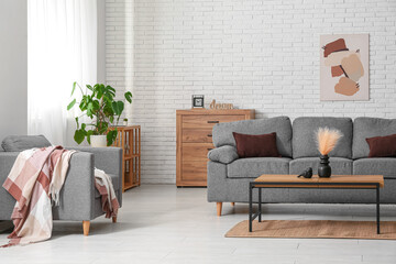 Interior of living room with comfortable grey sofa, armchair and table, closeup