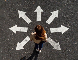 Woman silhouette stands in center of top down view of asphalt, surrounded by scattered arrows pointing in various directions, evoking sense of choice and contemplation