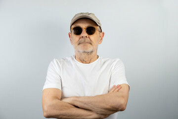 Senior Man Wearing Sunglasses and Hat Standing With Arms Crossed