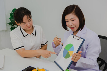 An Asian female nutritionist attentively discusses dietary habits with a patient, offering...