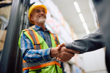 Close up of warehouse worker greeting female inspector.