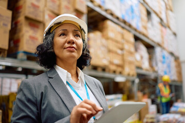 Female inspector using touchpad while working in distribution warehouse.