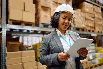 Mature businesswoman using digital tablet while working in distribution warehouse