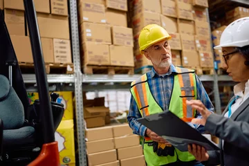 Gordijnen Warehouse foreman talking to female manager in storage compartment. © Drazen
