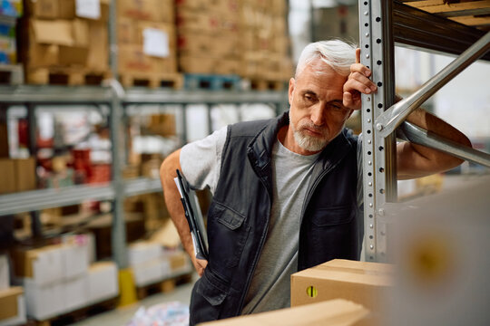Distraught warehouse worker taking break while working in storage room.