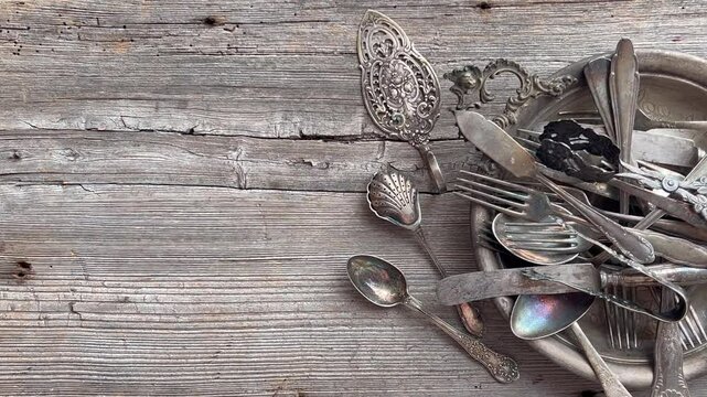 Rustic collection of vintage silverware on weathered wooden table for culinary decor. Vintage objects cutlery with patina.