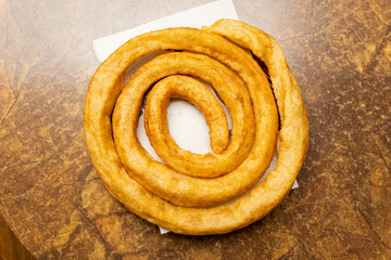 Overhead shot of a churro roll on a cafe table. The concept of porras or churros. Flour fried in oil.