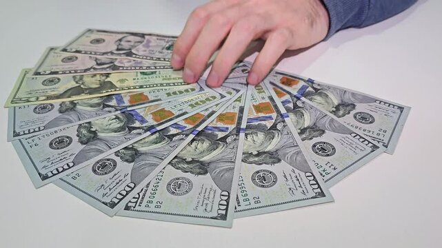 Hand taking fan of US dollar banknotes including 100 and 20 bills on white background. Close up photography. Money handling and cash payment concept. Design for poster, banner, print, card, wallpaper