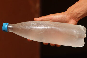 Hand holding a frozen water bottle