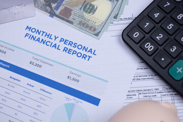 A monthly personal financial report with charts, cash, a calculator, and credit card visible, representing budgeting and expense tracking.