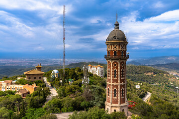 View of the Torre De Les Aigues De Dos Rius water tower on top of Tibidabo hill in amusement park in summer, with Mediterranean sea in background, Barcelona, Spain