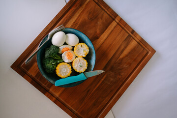 Healthy vegetarian breakfast with eggs, broccoli and corn on wood plate