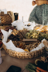 Outdoor picnic table with fresh fruits, vegetables, snacks, and wooden cutlery in warm natural light. Rustic and eco-friendly food setup.