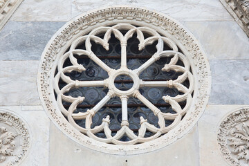 Medieval italian rose window against a stone wall - Italy
