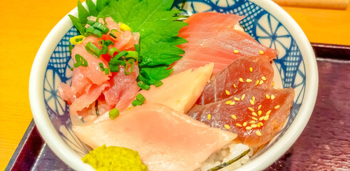 Rice bowl with raw fish and seafood, tuna, salmon, sea bass, and wasabi in Japanese style restaurant