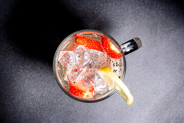 Top view of a refreshing cocktail of pitahaya and strawberry pieces with ice and lemon.