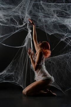 Fototapeta Red-haired woman entangled in a net trap resembling a spider web