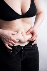 Naklejka premium Caucasian woman are overweight. She has excess fat around her stomach. Must lose weight Exercise concept to break down the fat under your skin 