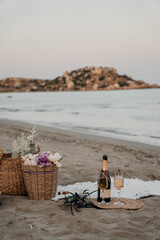 Romantic champagne setup on the beach with two elegant glasses, coastal flowers, and sea view. Cozy sunset picnic with natural textures and soft light.