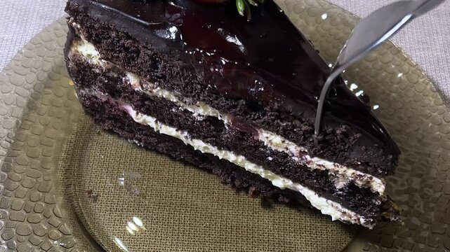 Horizontal video close up. Fork breaks off juicy red fresh piece of chocolate brown cake with strawberry on plate. Berry on sweets for birthday. Concept of healthy food, eat, lunch, sweet shop, dinner